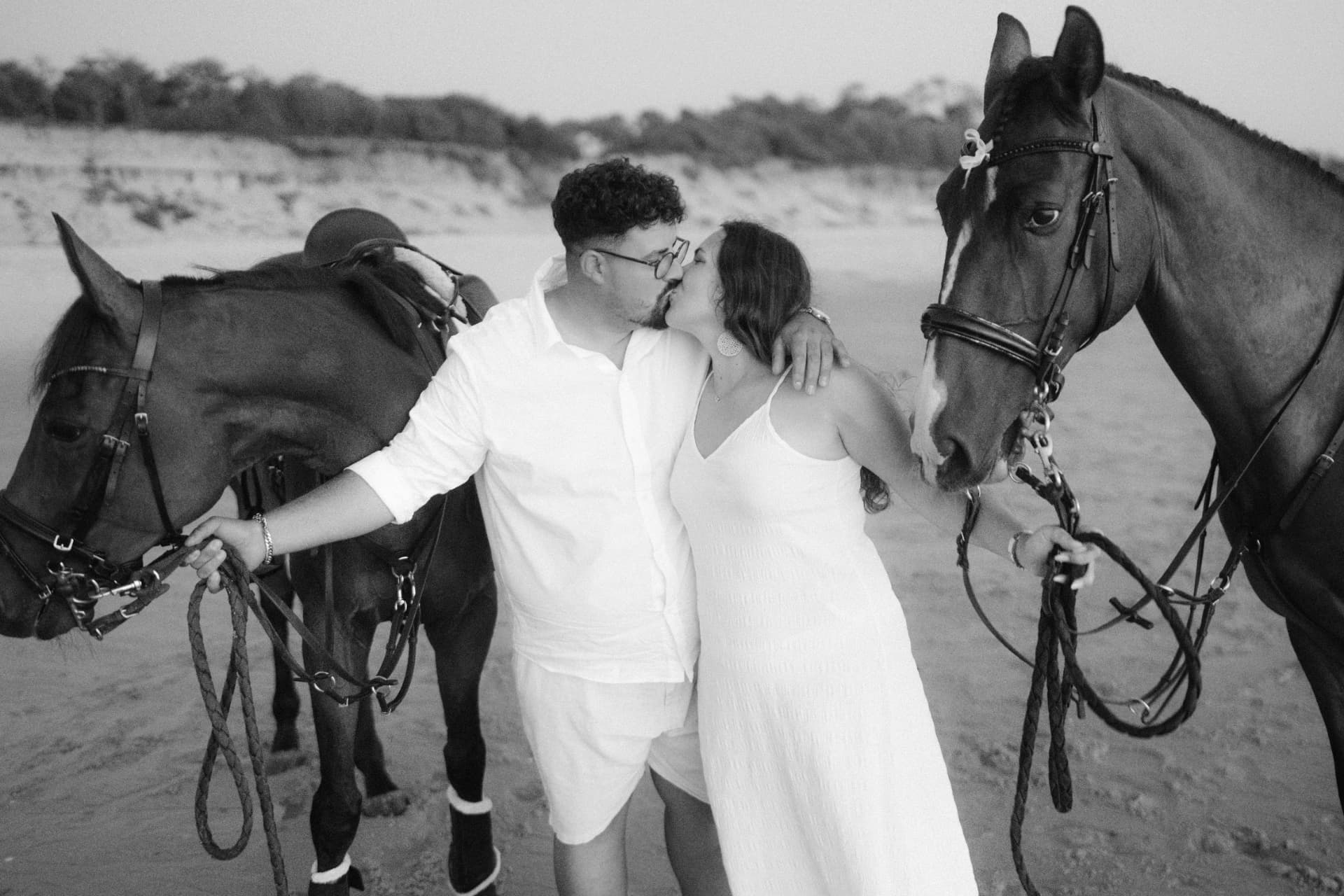 Os noivos a beijar-se entre dois cavalos